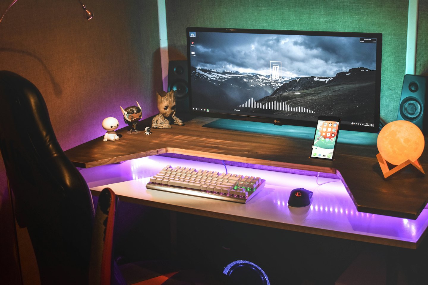 Modern L-shaped desk with gaming figurines and RGB lighting.
