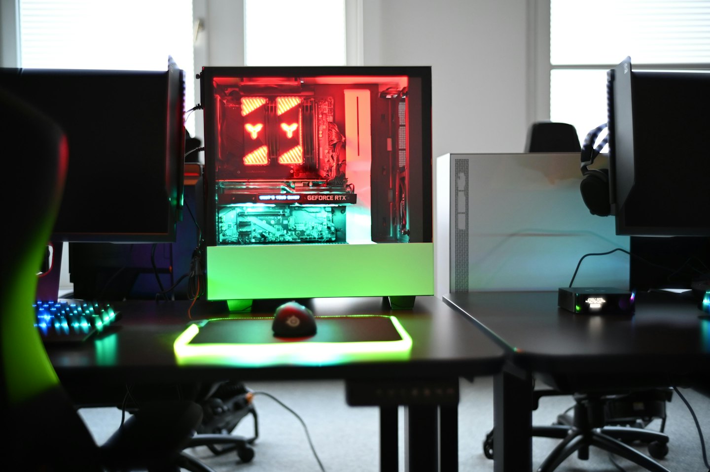 Custom gaming PC with red and green RGB lighting and dual monitors.