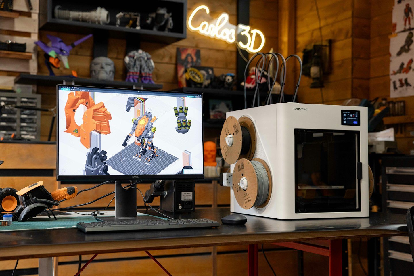 3D printer and computer displaying robot model on wooden desk.